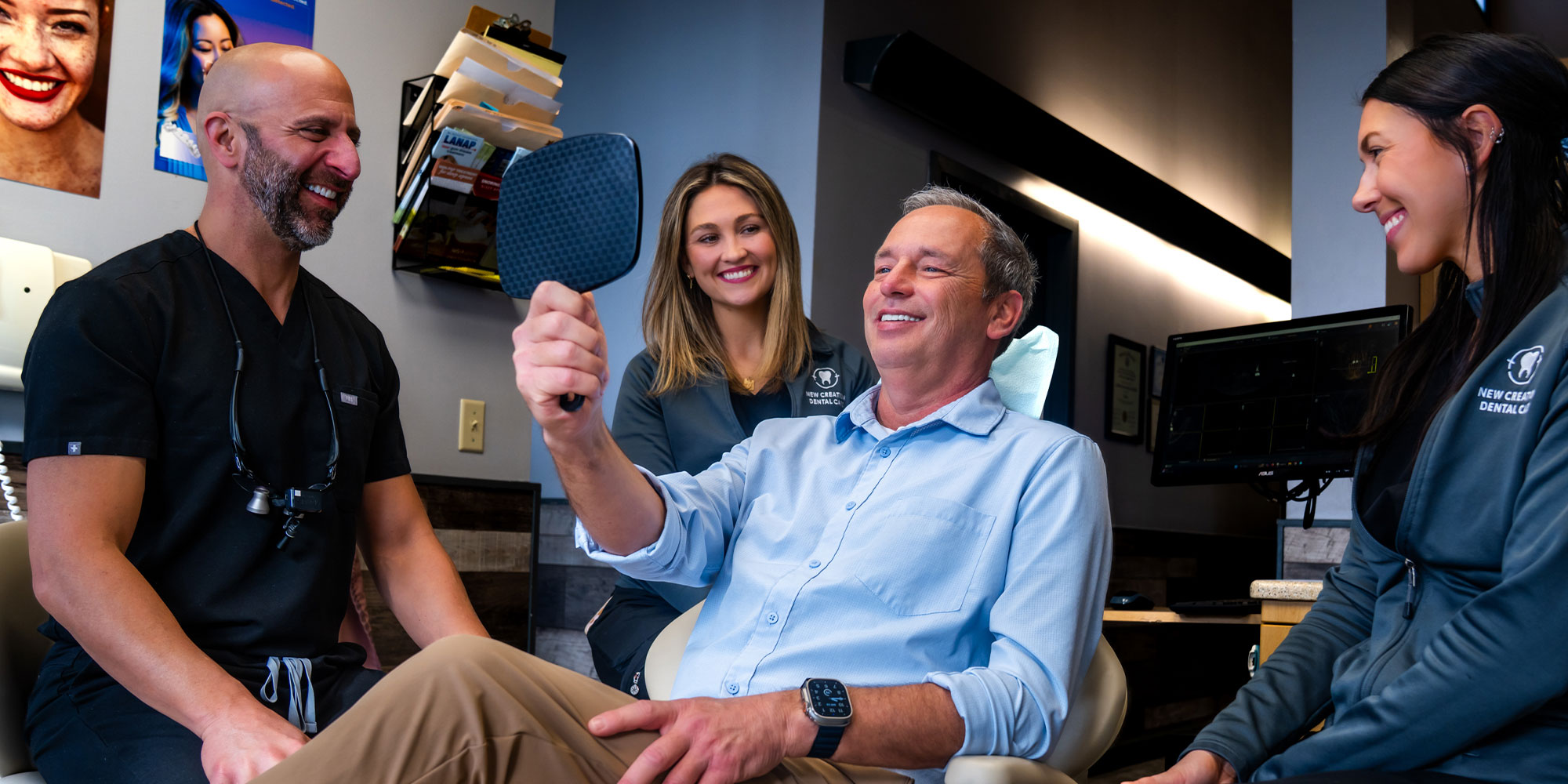Patient looking into mirror smiling with doctor and team members